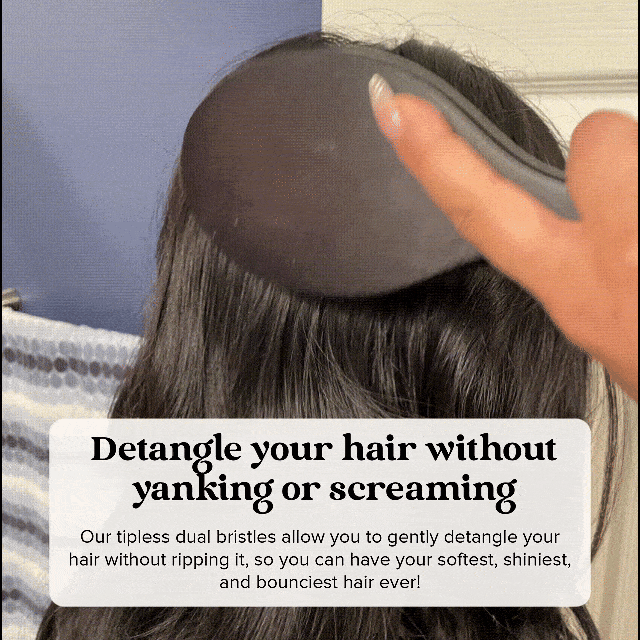 A hand brushing long, dark hair with a detangling brush.