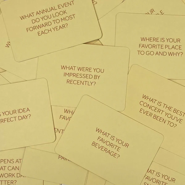 A scattered pile of pale yellow cards, each with a printed question on it.