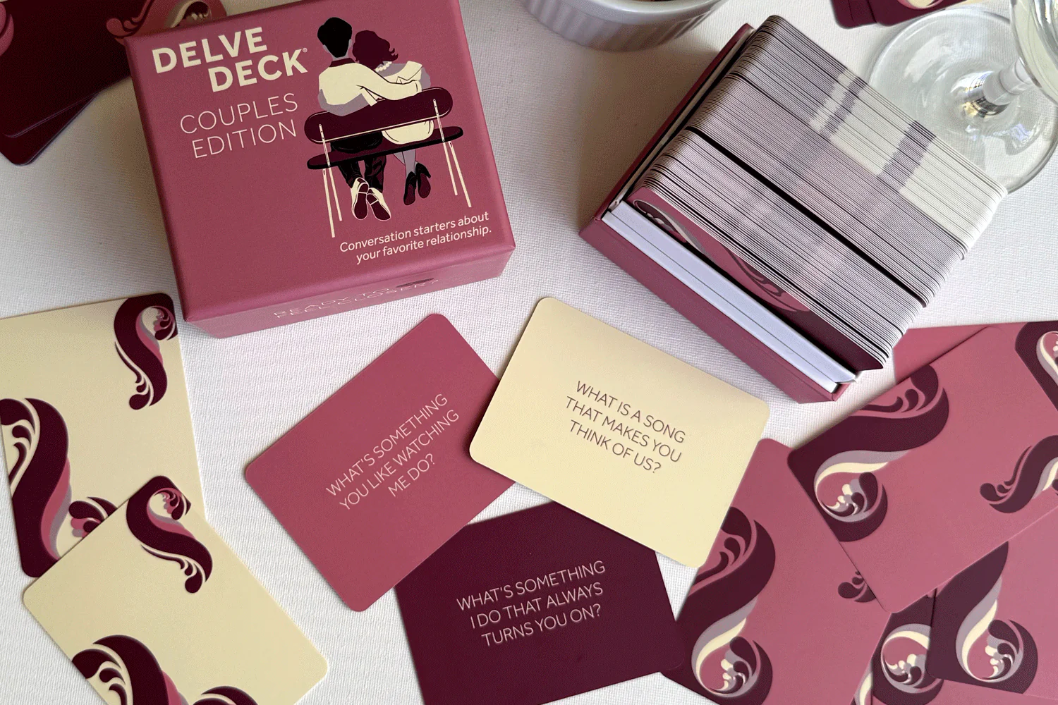 The Delve Deck Couples Edition card game box and several cards with conversation starters spread on a surface.