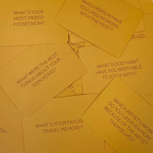 A pile of yellow cards, each with a different conversation-starting question printed on it.