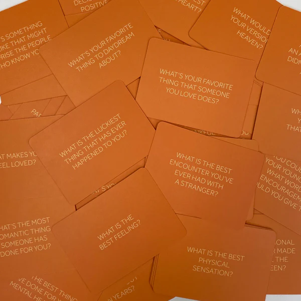 A pile of scattered orange cards, each with a question printed on it in white text.