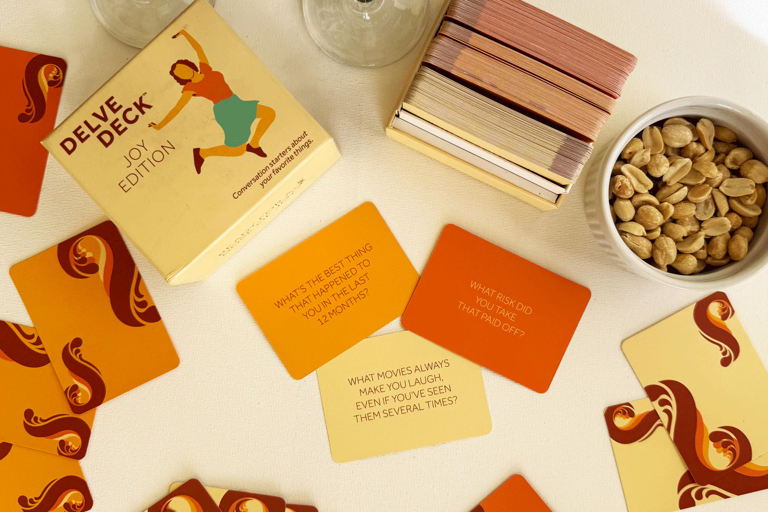 A card game called Delve Deck Joy Edition is laid out on a table with a bowl of peanuts.