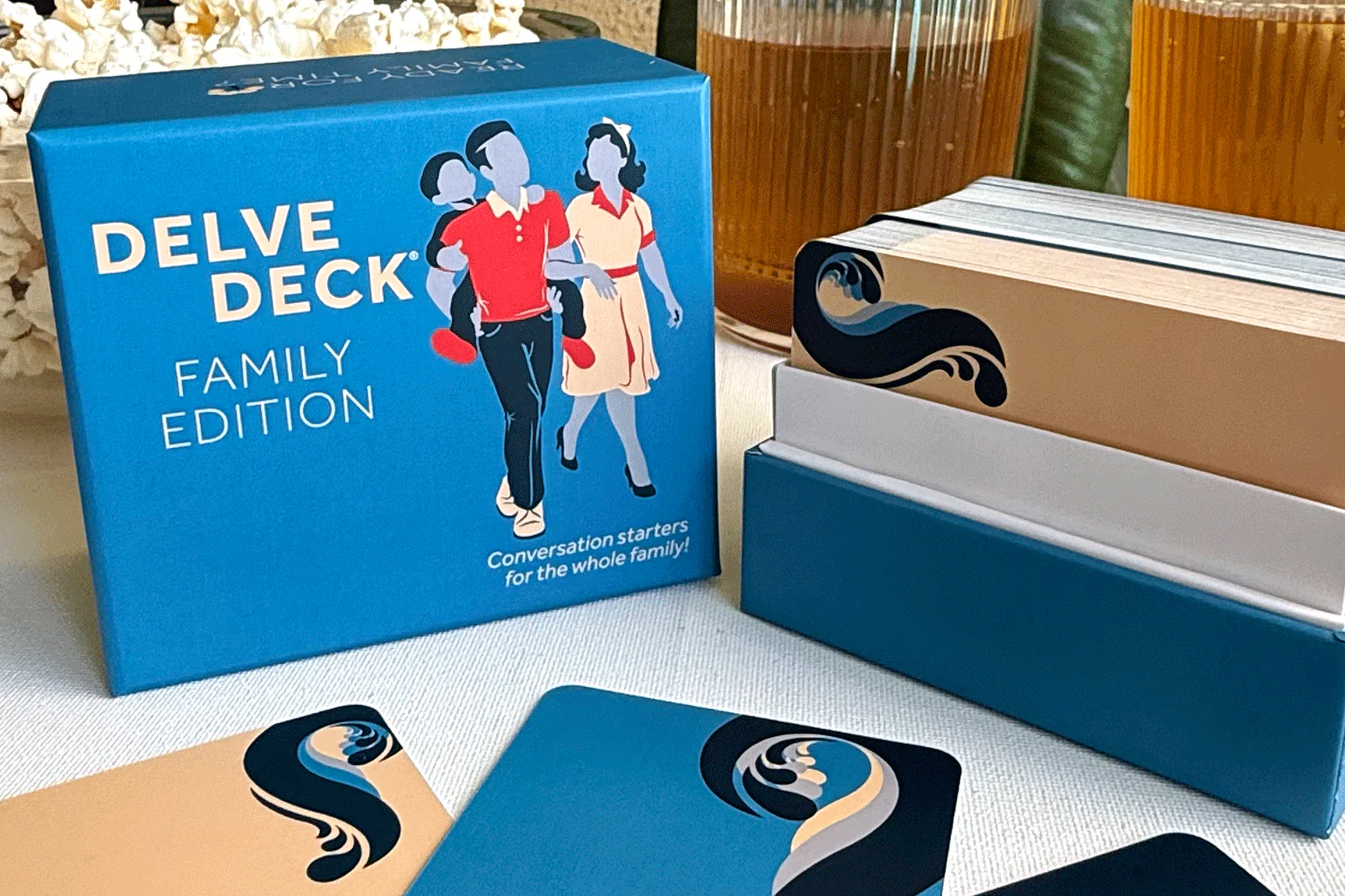 The Delve Deck Family Edition card game, with its box and cards displayed on a table.
