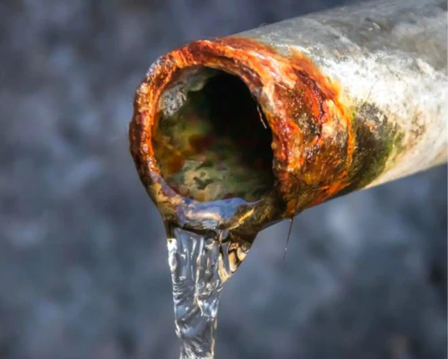 Rusty metal pipe with water flowing out.