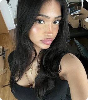Person with long dark hair taking a selfie indoors.