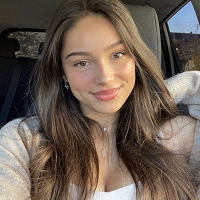Person with long hair smiling inside a car.