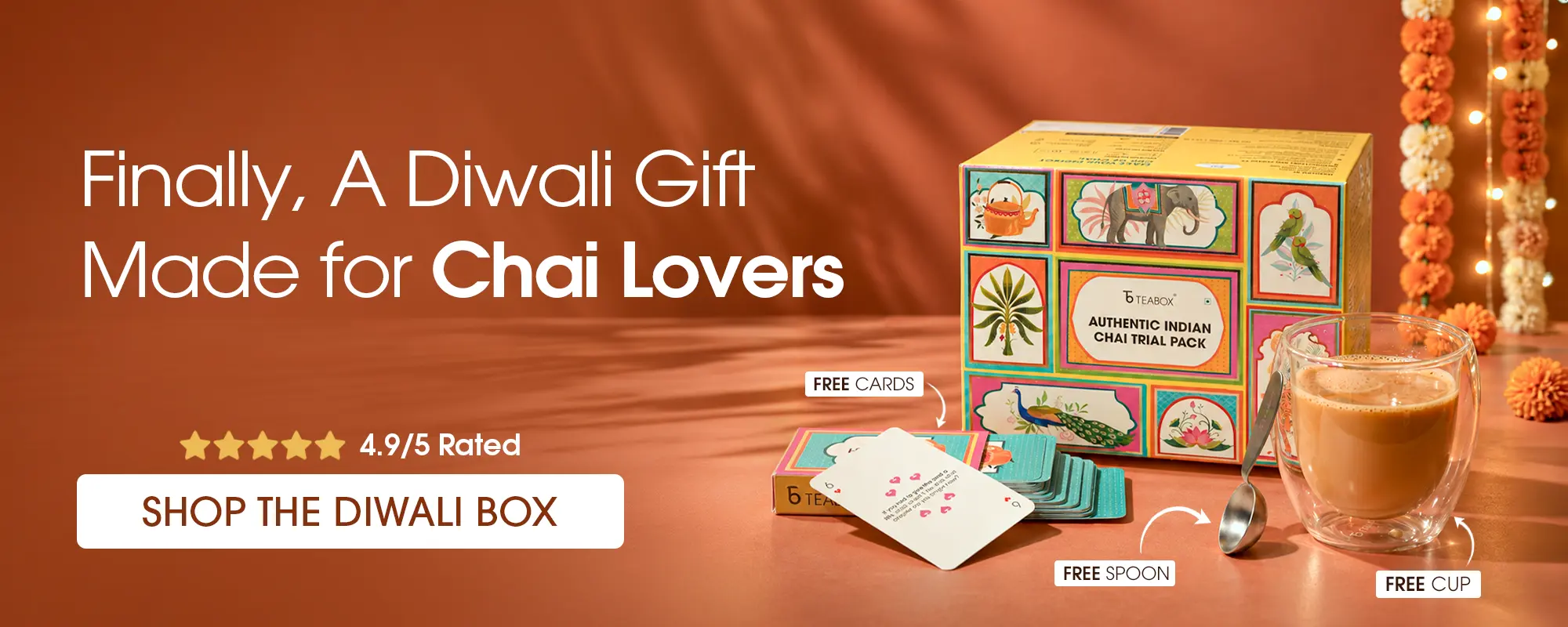 A colorful Teabox chai gift set shown with a glass of chai, a spoon, and cards.