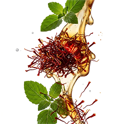 Saffron threads and green mint leaves suspended in a stream of golden liquid against a white background.