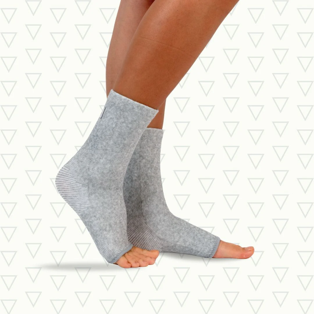 Person wearing gray ankle compression sleeves on both feet.
