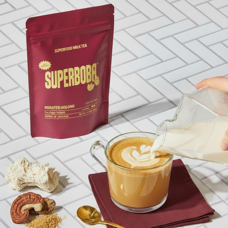 Pouring milk into a cup of coffee next to a packet of SuperBoba.