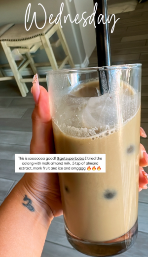 Hand holding a glass of iced milk tea with a straw.