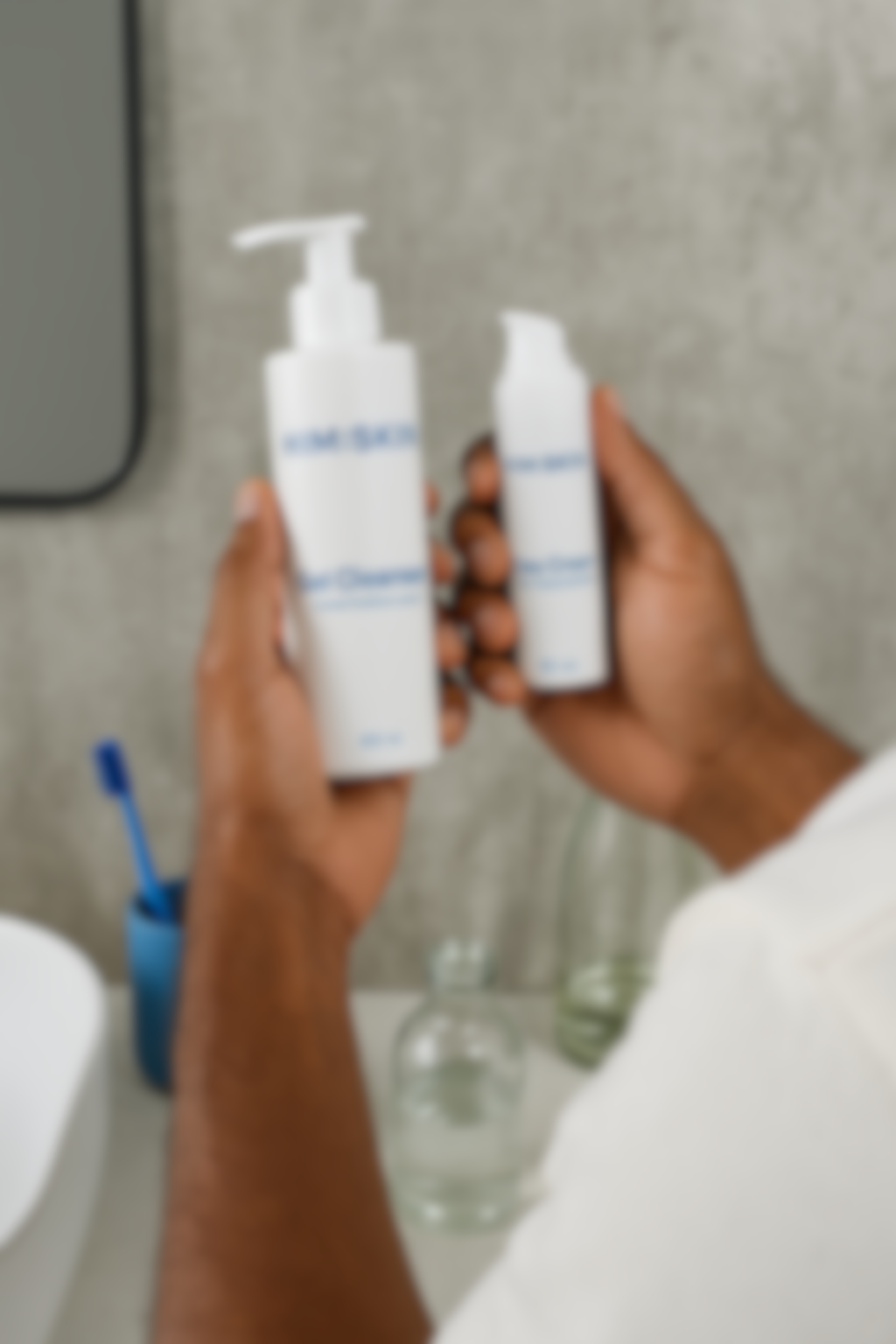 Person holding two bottles of skincare products in a bathroom.