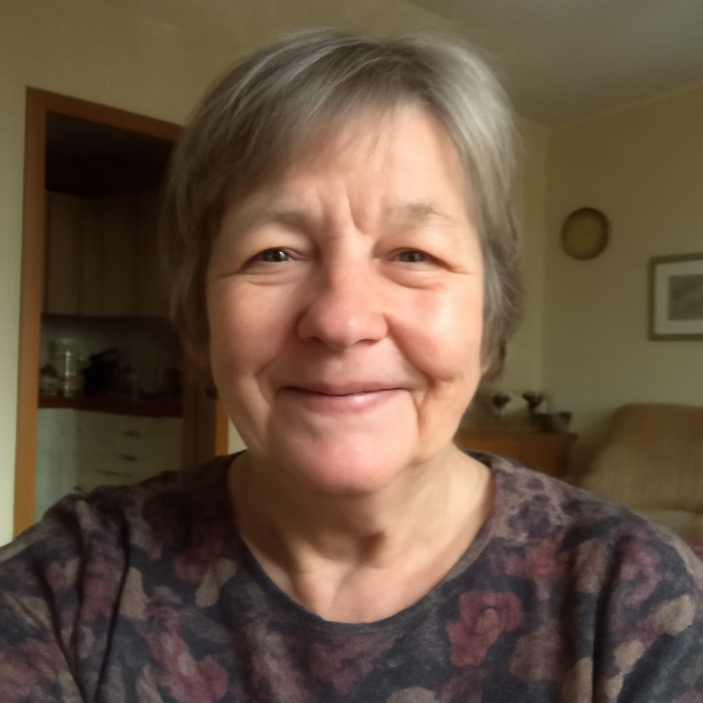 Smiling person with short gray hair in a cozy room.