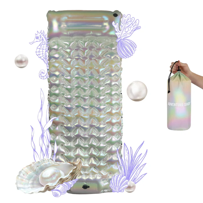 Iridescent inflatable mattress with seashell and seahorse illustrations, and a hand holding a matching bag.