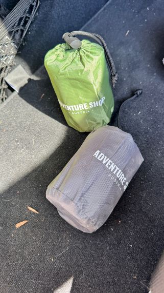 Two small bags labeled 'Adventure Shop' on a car floor.