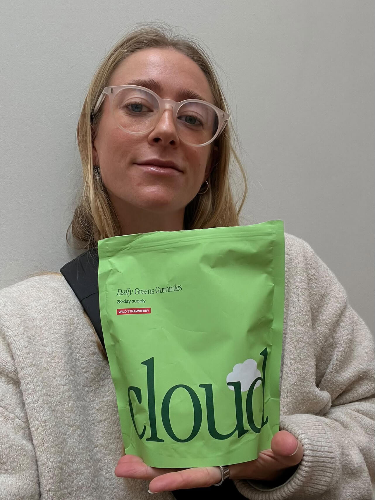 Person holding a green bag labeled 'cloud' with Daily Greens Gummies.