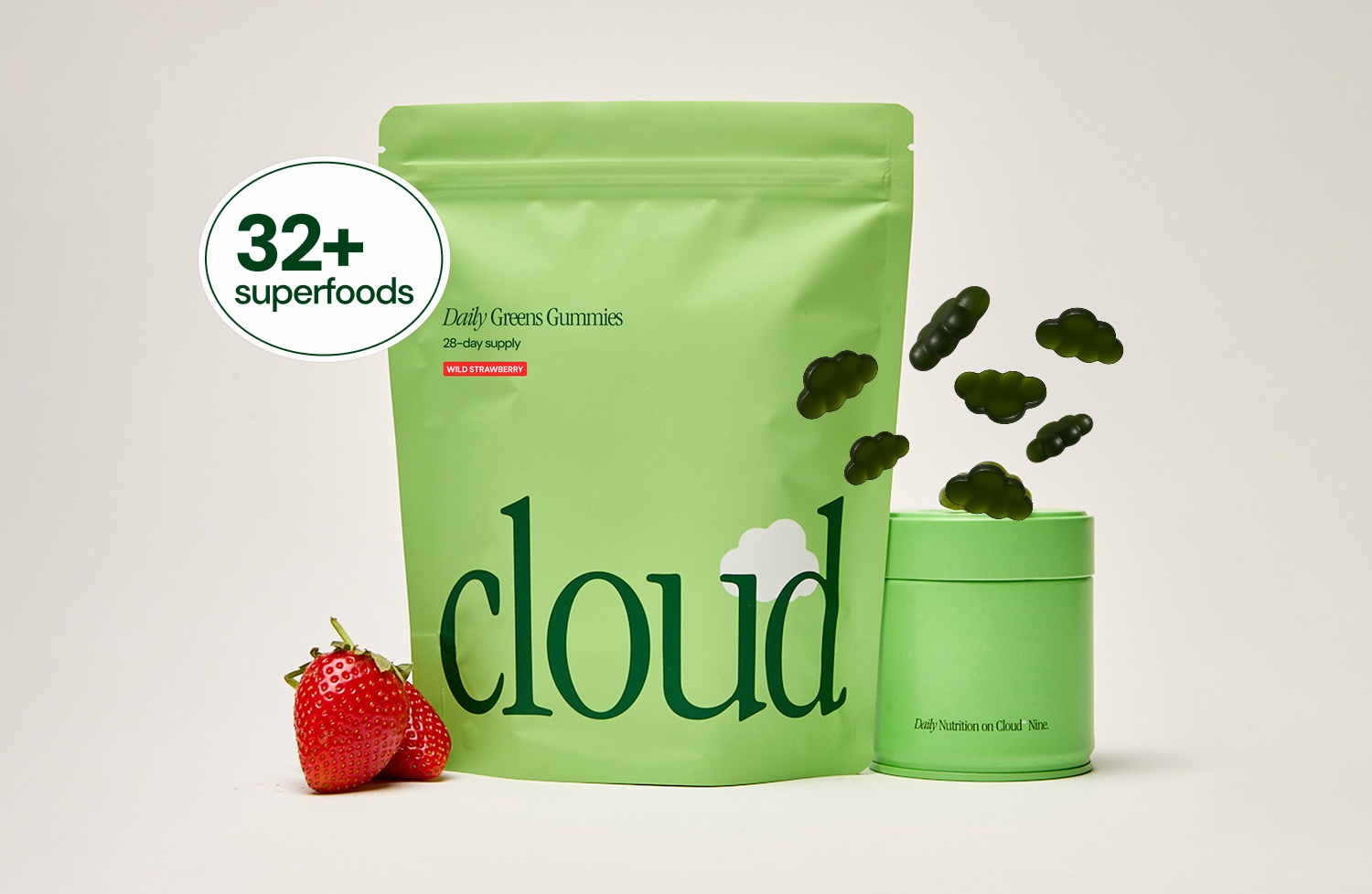 A green pouch of Cloud Daily Greens Gummies next to a container, strawberries, and cloud-shaped gummies.