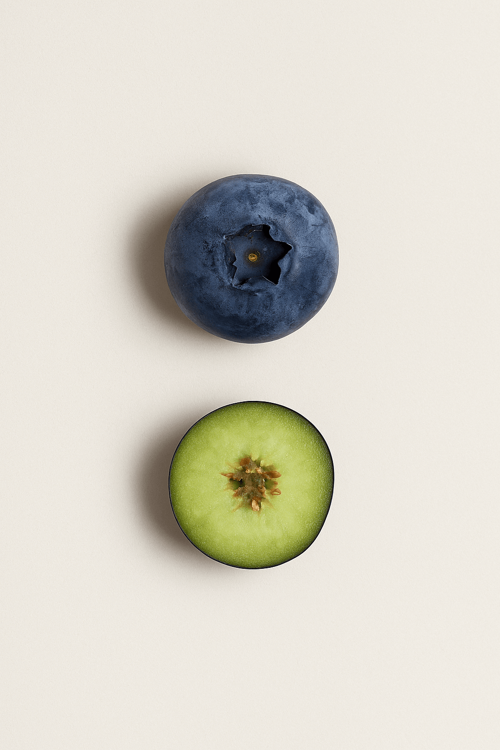 A whole blueberry and a sliced grape on a light background.