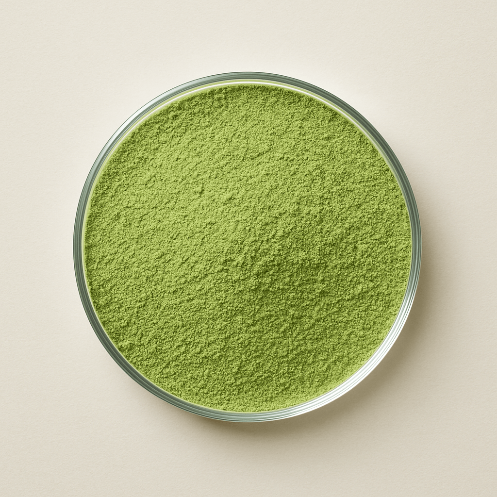 Glass bowl filled with green powder on a beige background.