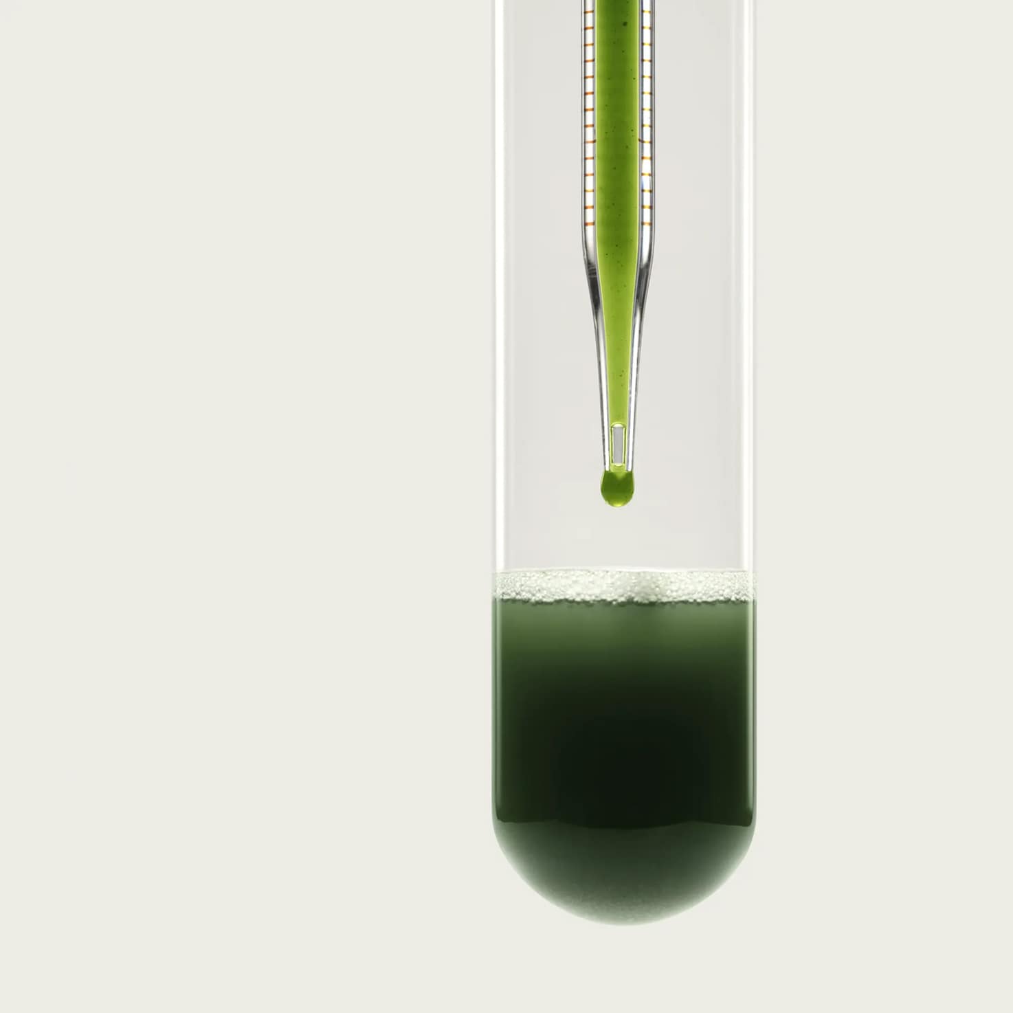 Test tube with green liquid and a green dropper inside.