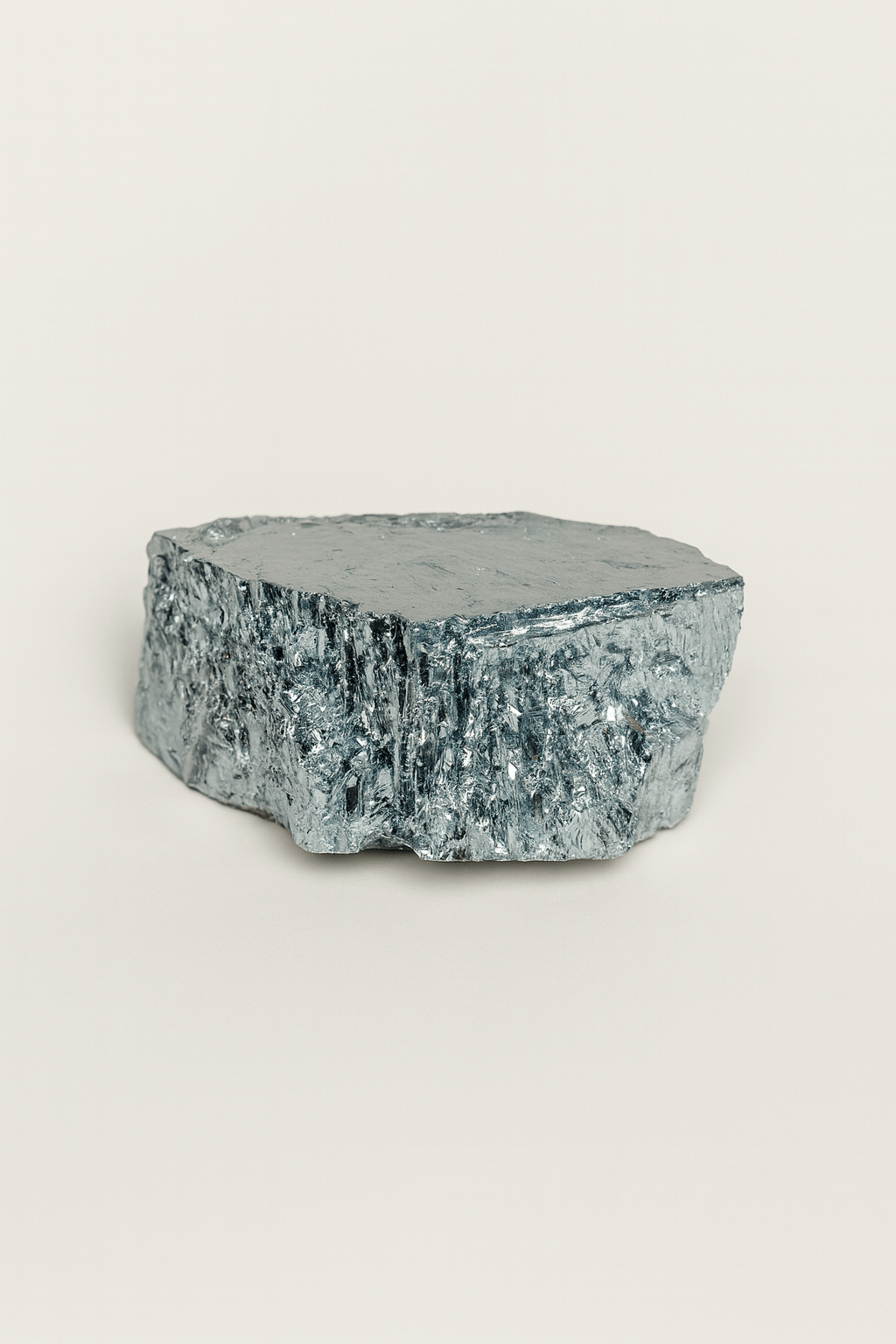 A close-up of a silver-colored, textured metal ingot on a plain background.