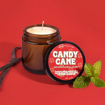 A brown jar candle labeled 'Candy Cane' sits on a red background with vanilla beans and mint leaves.