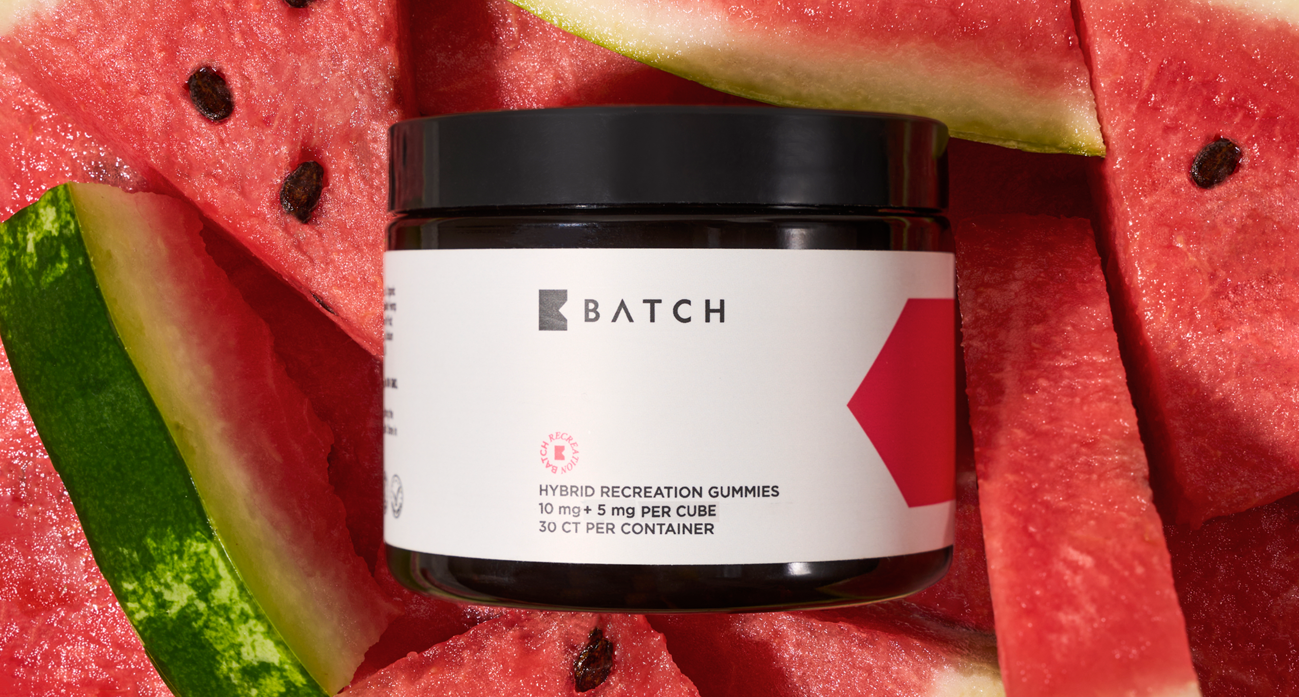 Jar of gummies surrounded by watermelon slices.