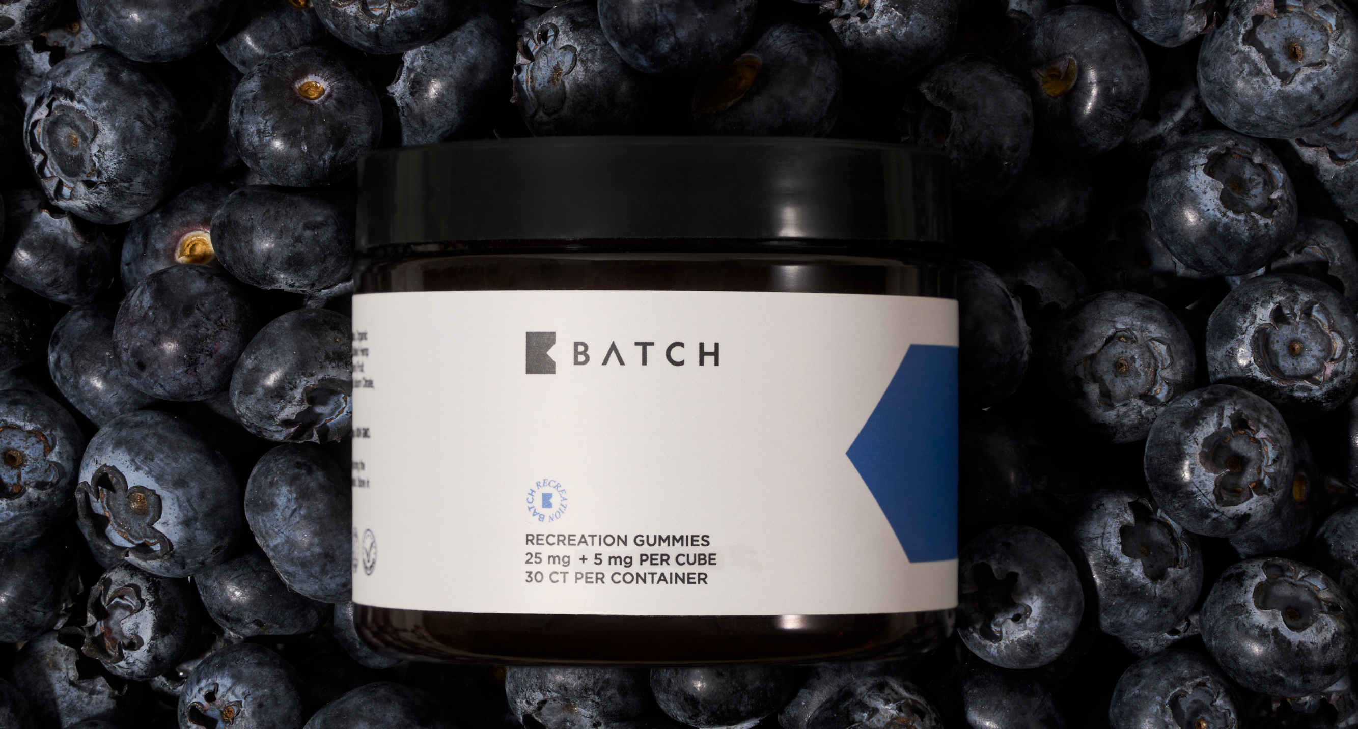 Jar of gummies labeled 'Batch' surrounded by fresh blueberries.