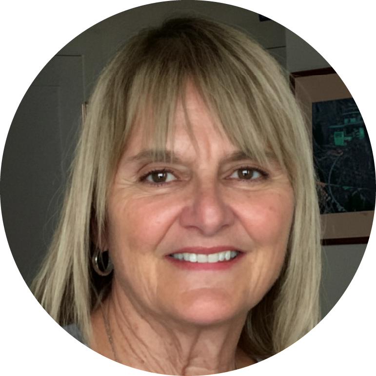 A person smiling with light hair, wearing earrings, in a circular-cropped image.