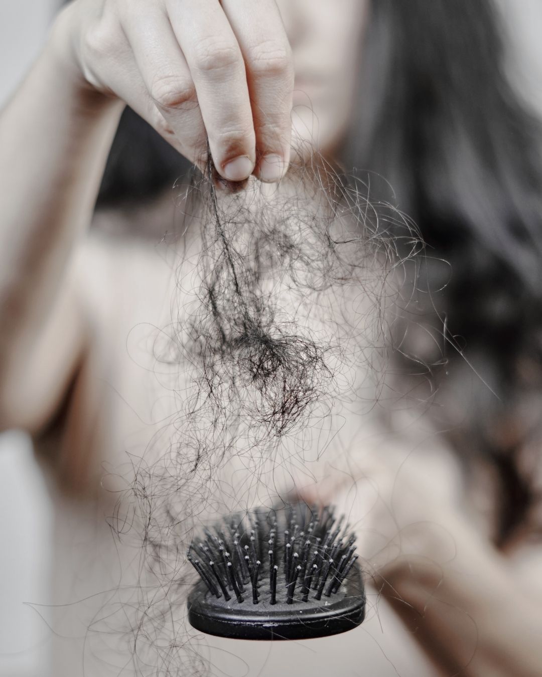 Hand holding a clump of hair over a hairbrush.