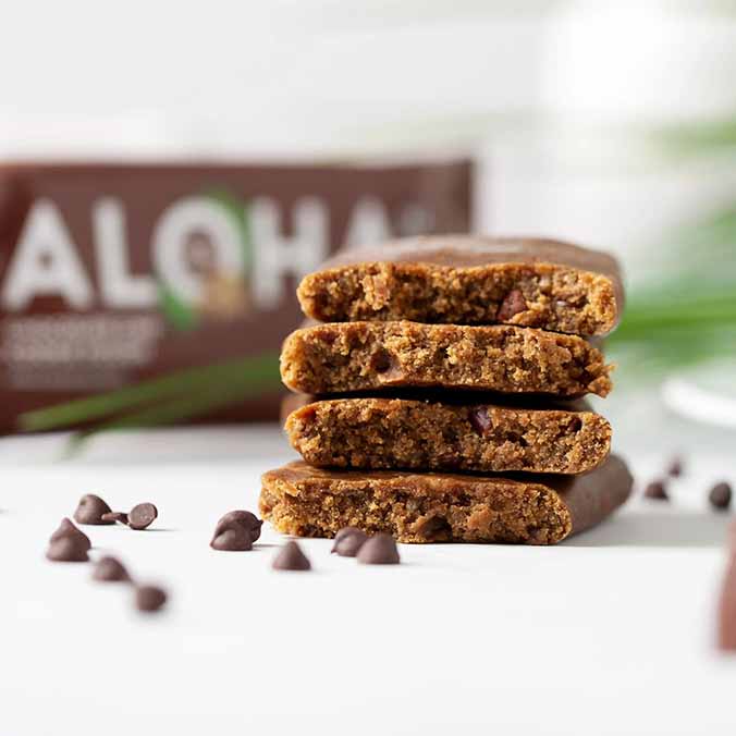 Stacked chocolate chip protein bars with scattered chips on a white surface.