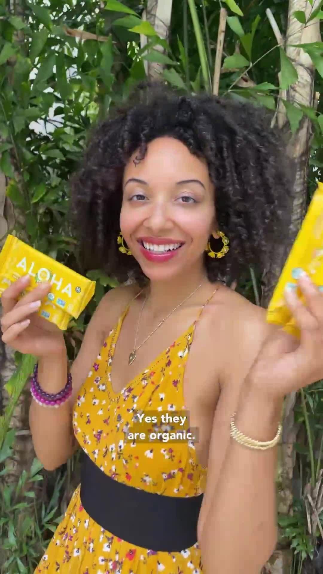 Woman smiling, holding two yellow Aloha bars, with text: 'Yes they are organic.'