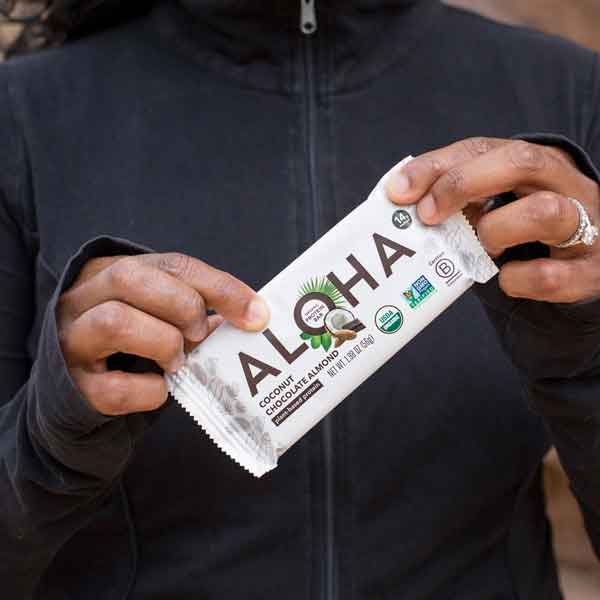 Person holding an Aloha Coconut Chocolate Almond protein bar.