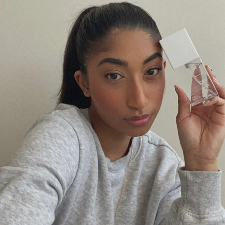 Person holding a clear bottle with a white cap, wearing a gray sweatshirt.