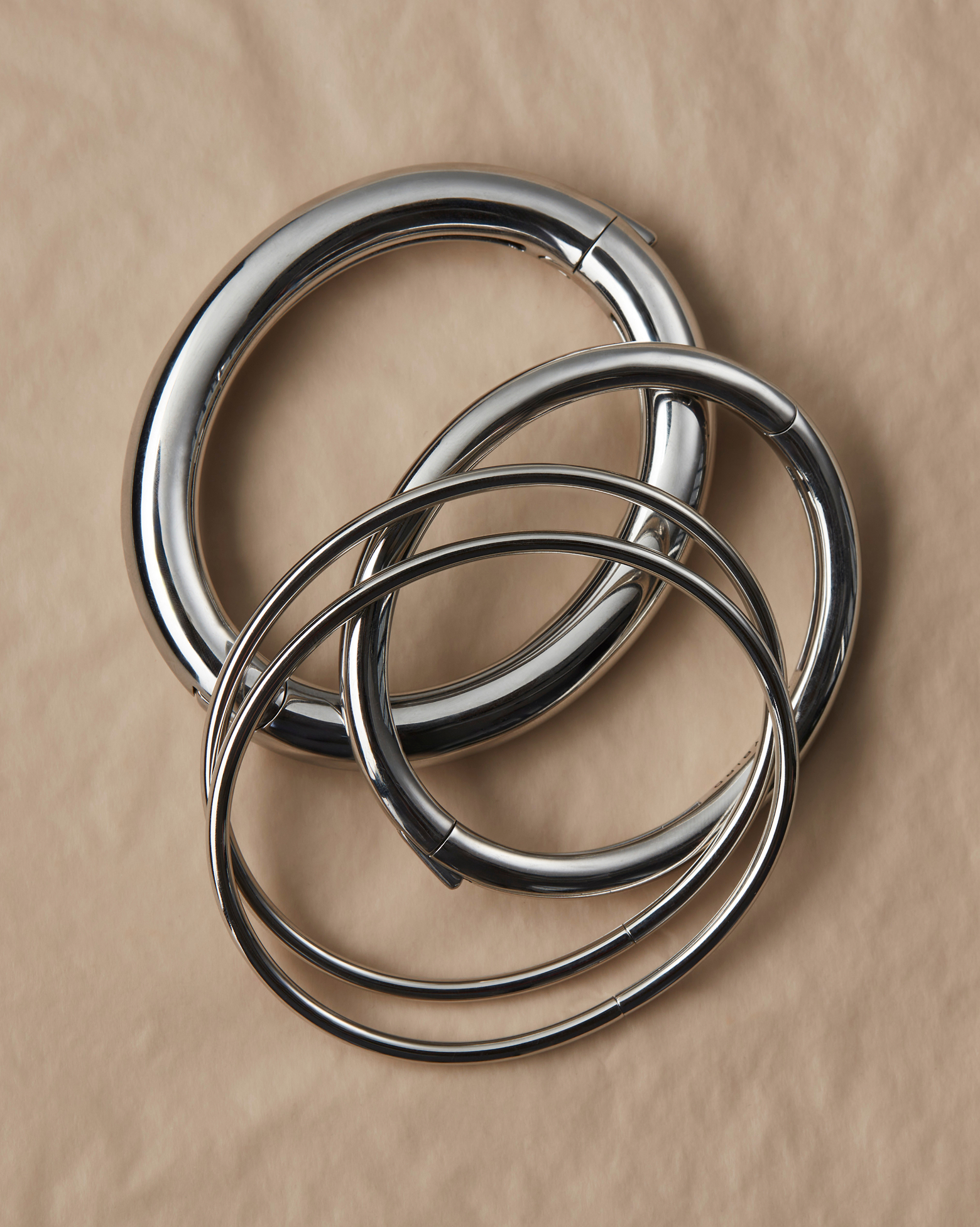Three interlocking silver rings on a beige background.