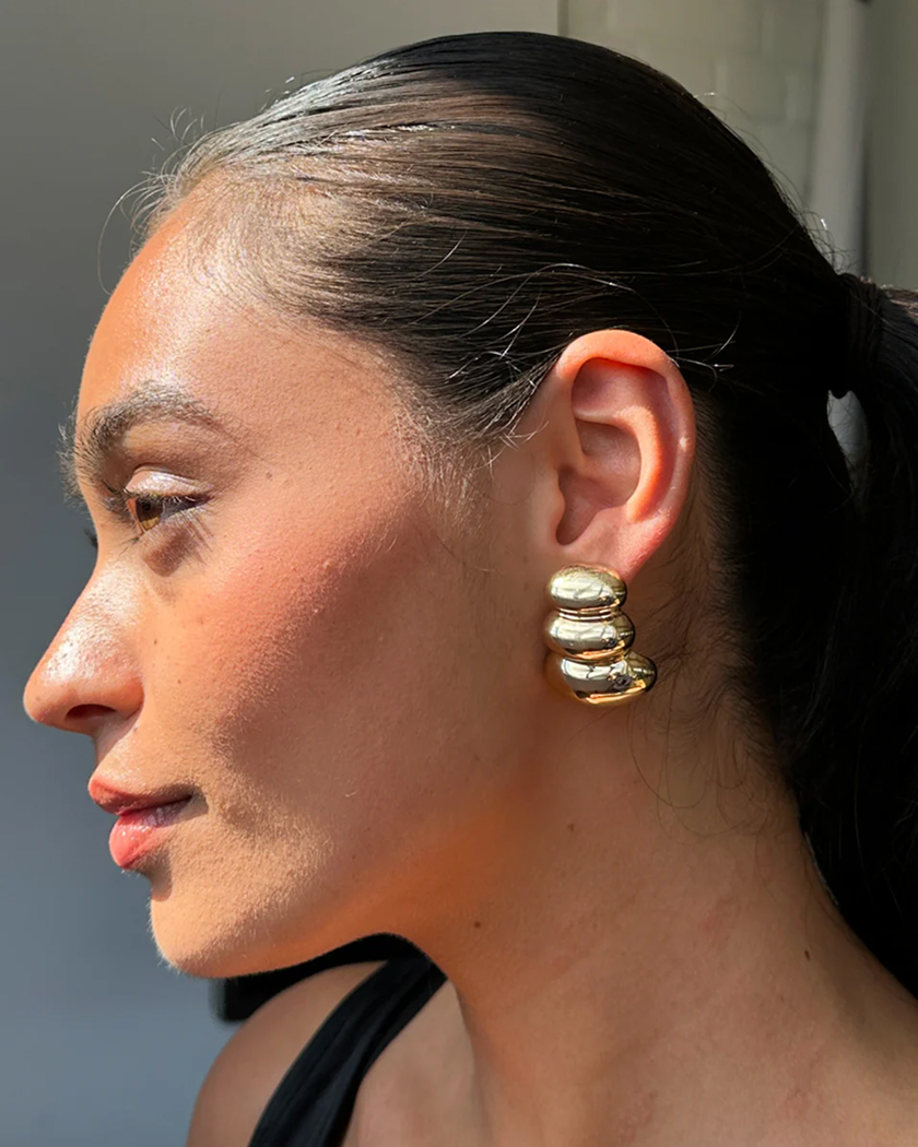 Person wearing large gold hoop earrings with a sleek hairstyle.