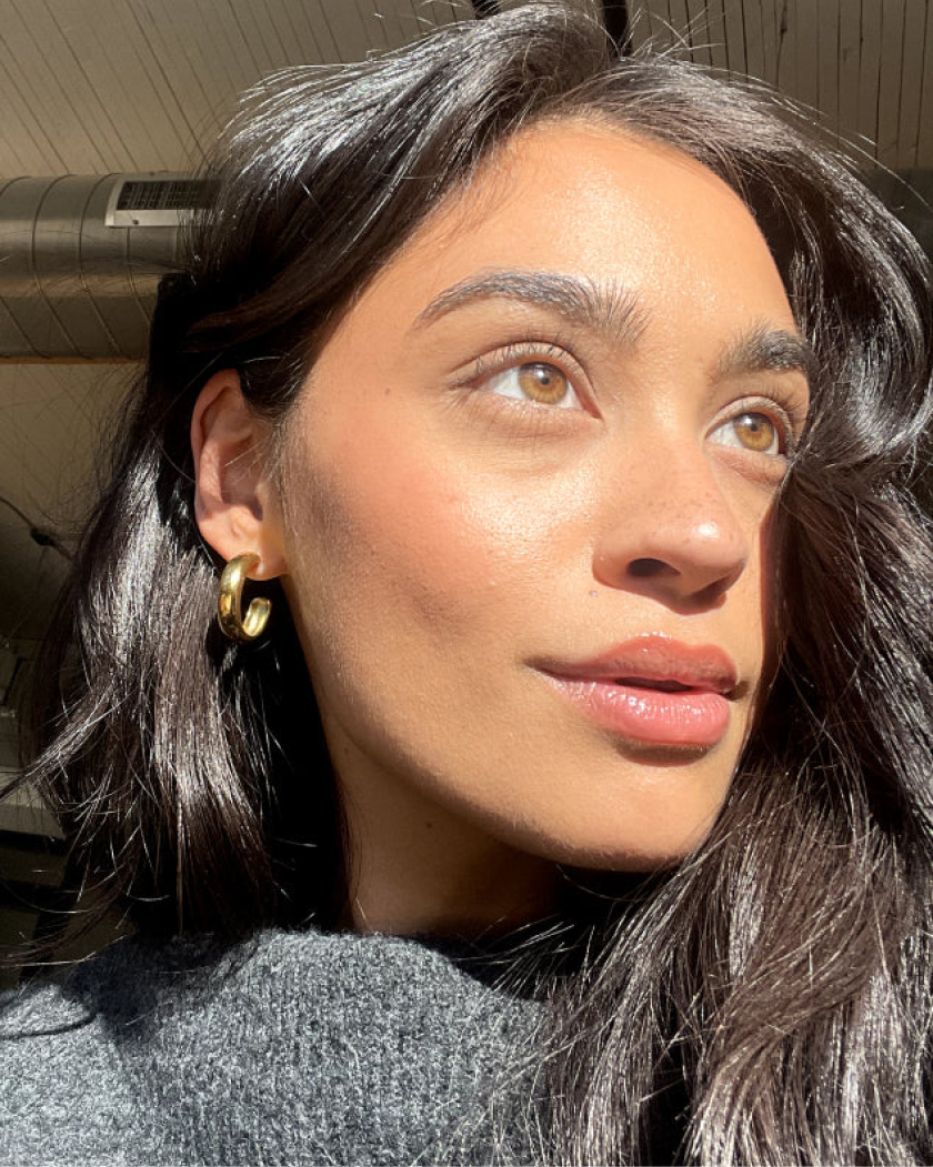 Close-up of a woman with long hair and gold hoop earrings.
