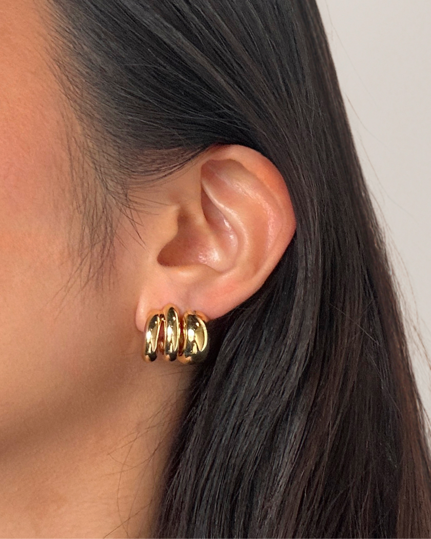 Close-up of an ear wearing a gold hoop earring.