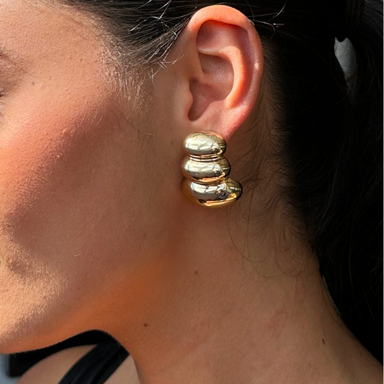 Close-up of a gold, stacked earring on a woman's ear.