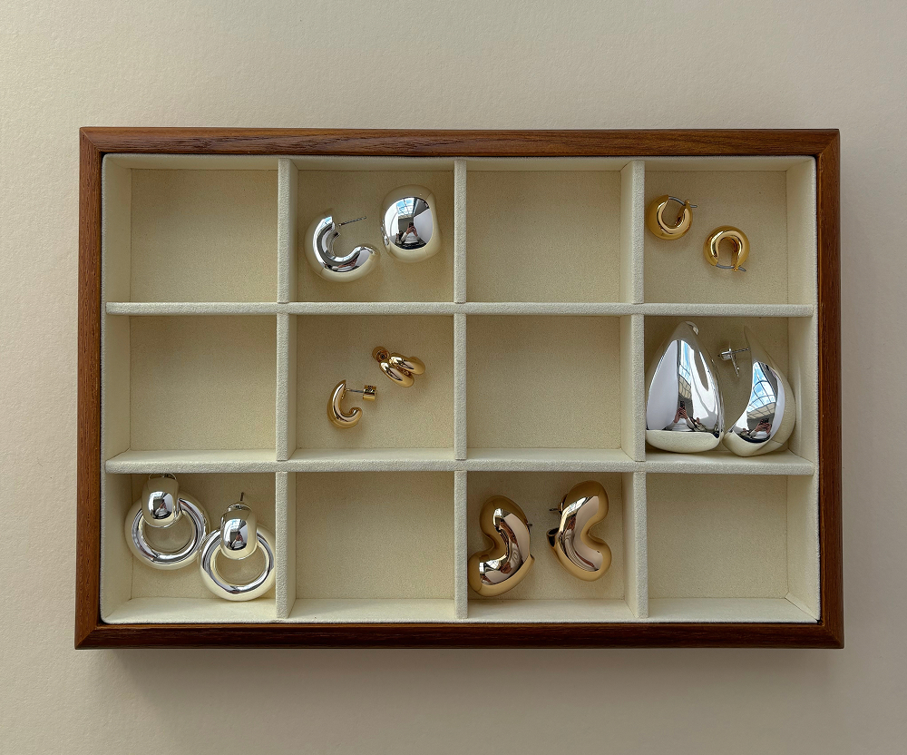 Wooden display case with various silver and gold earrings.