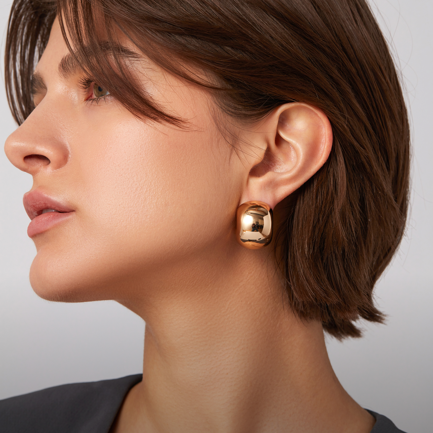 A person wearing a large gold earring, side profile view.