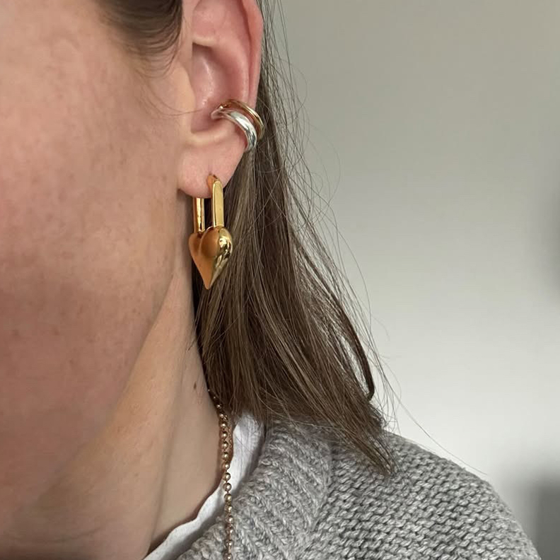 Close-up of an ear wearing gold and silver earrings.