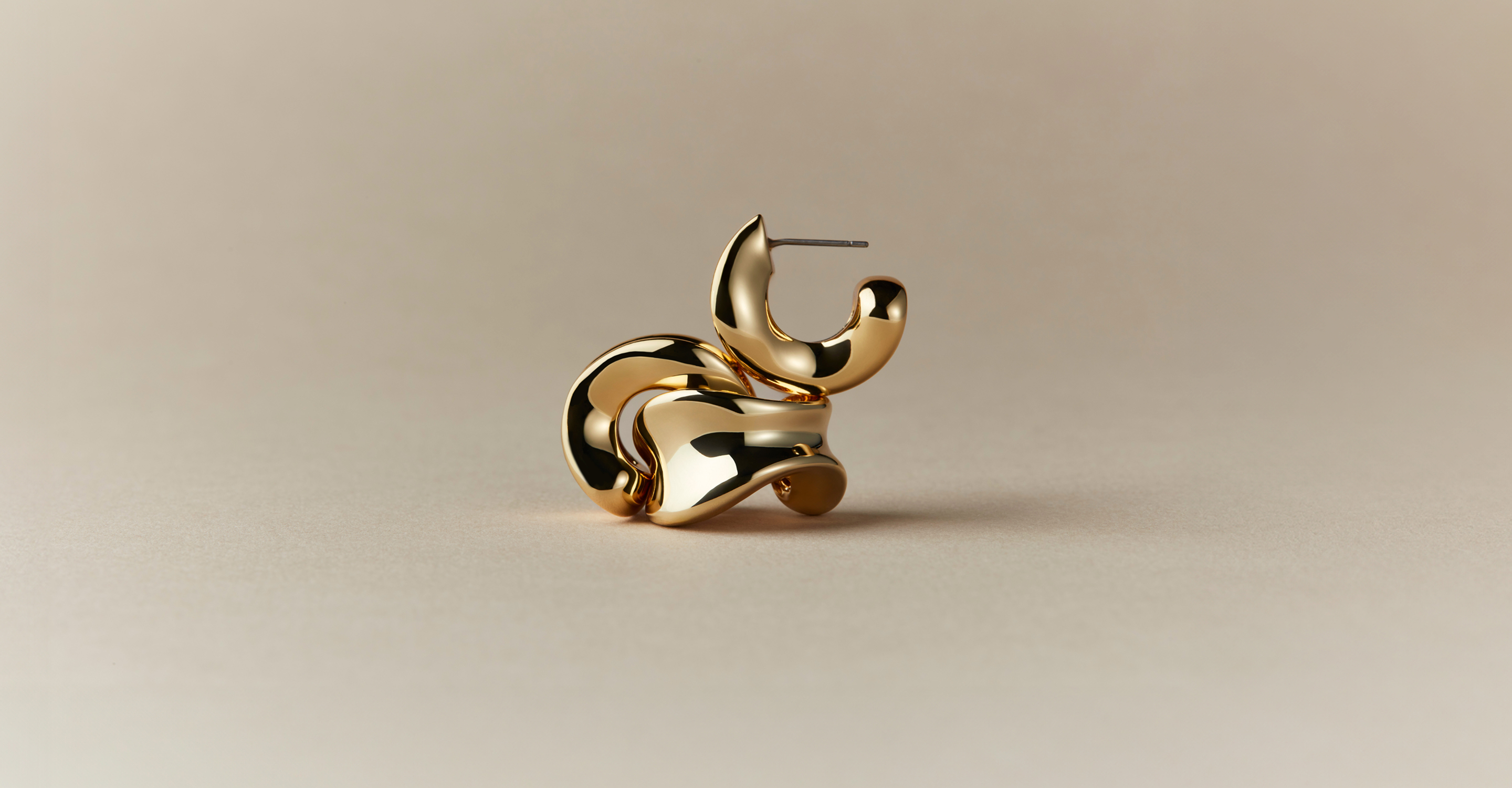 Gold and silver sculptural, chunky hoop earrings on a textured surface, emphasizing versatility and lightweight design.