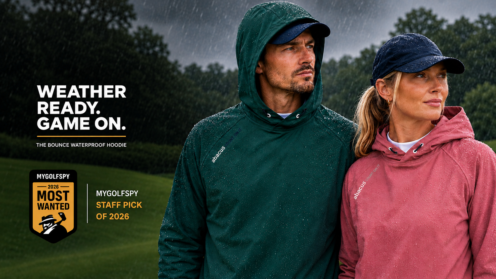 A man and a woman wearing waterproof hooded jackets stand on a golf course in the rain.