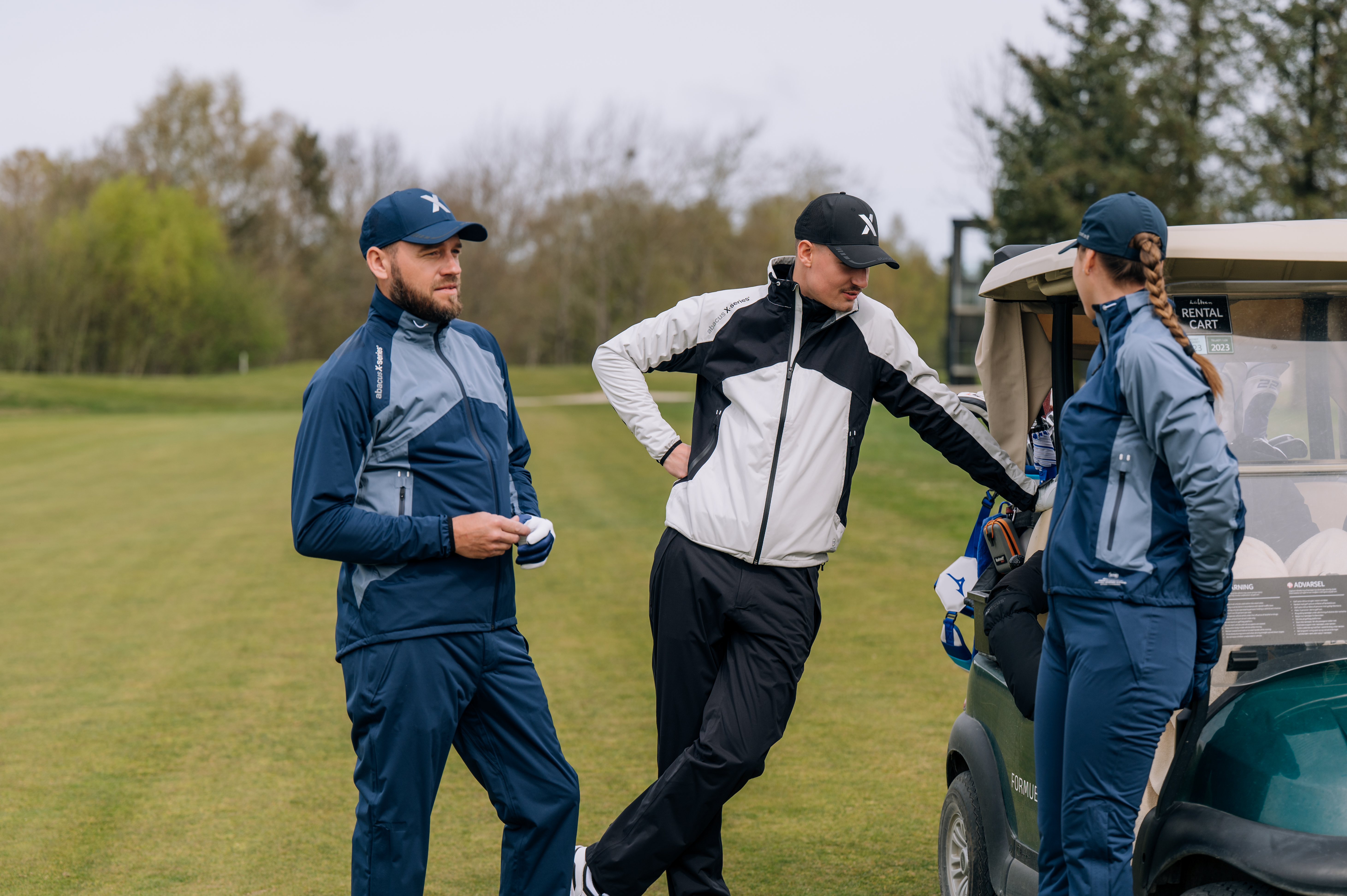 Two people in rain gear walking on a golf course.