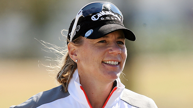 Person wearing a Callaway cap and white jacket, smiling outdoors.
