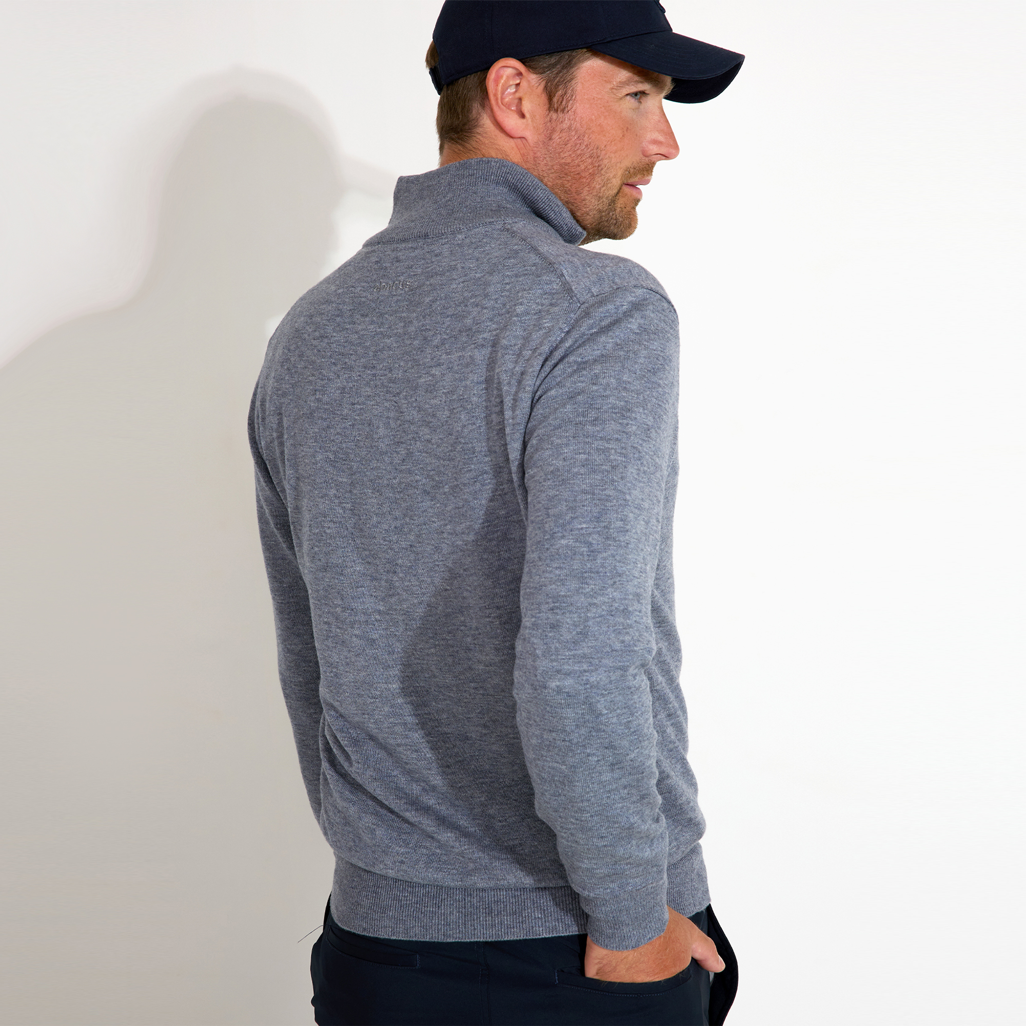 Man in gray sweater and cap seen from the side.