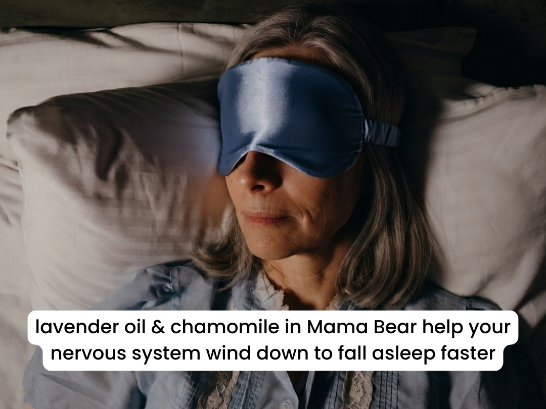 An older woman with gray hair wearing a blue satin sleep mask rests in bed.