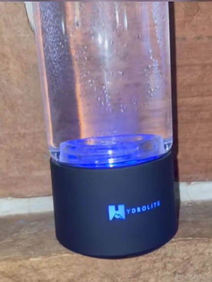 A clear water bottle with 'Hydrolite' on the black base, emitting blue light.