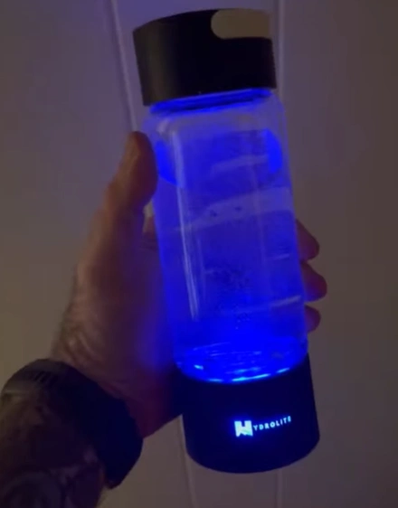 Hand holding a blue illuminated water bottle.